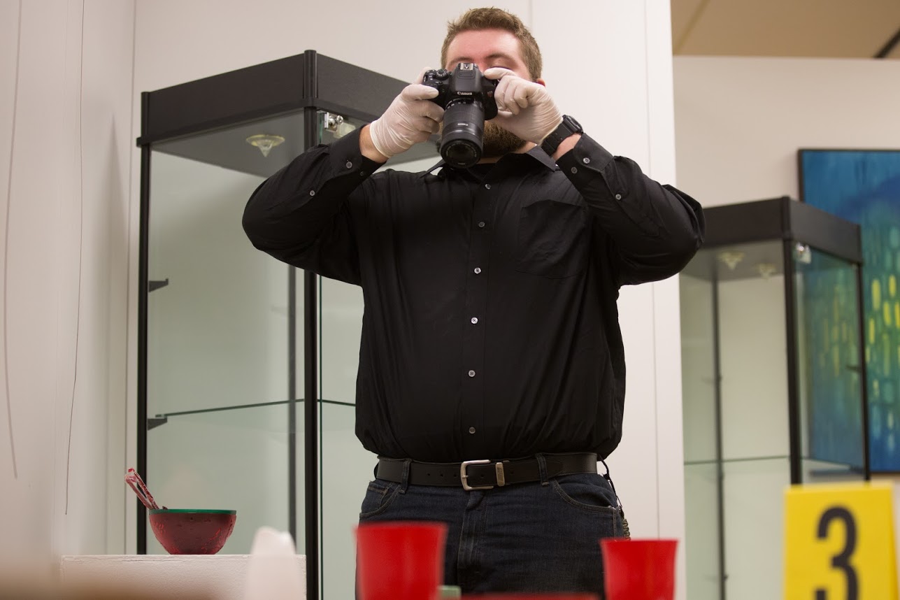 A man uses a camera to document evidence.