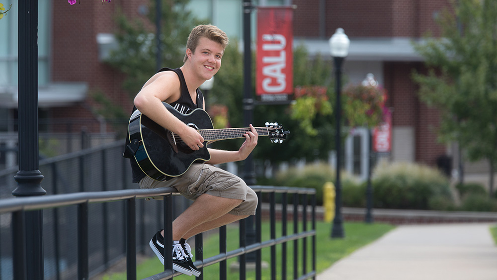 A student plays the guitar on campus.